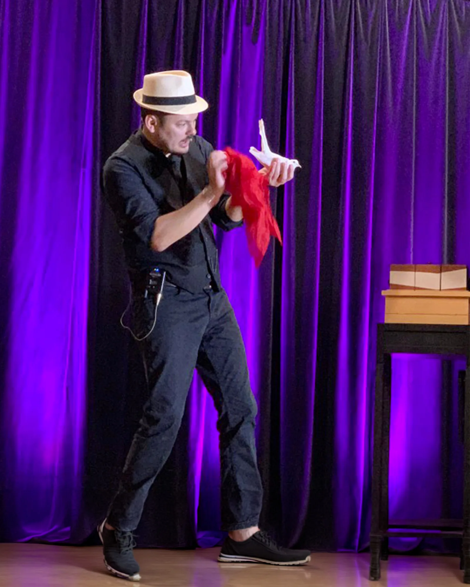 Jérôme sur scène, un foulard rouge jaillissant de sa table de magie