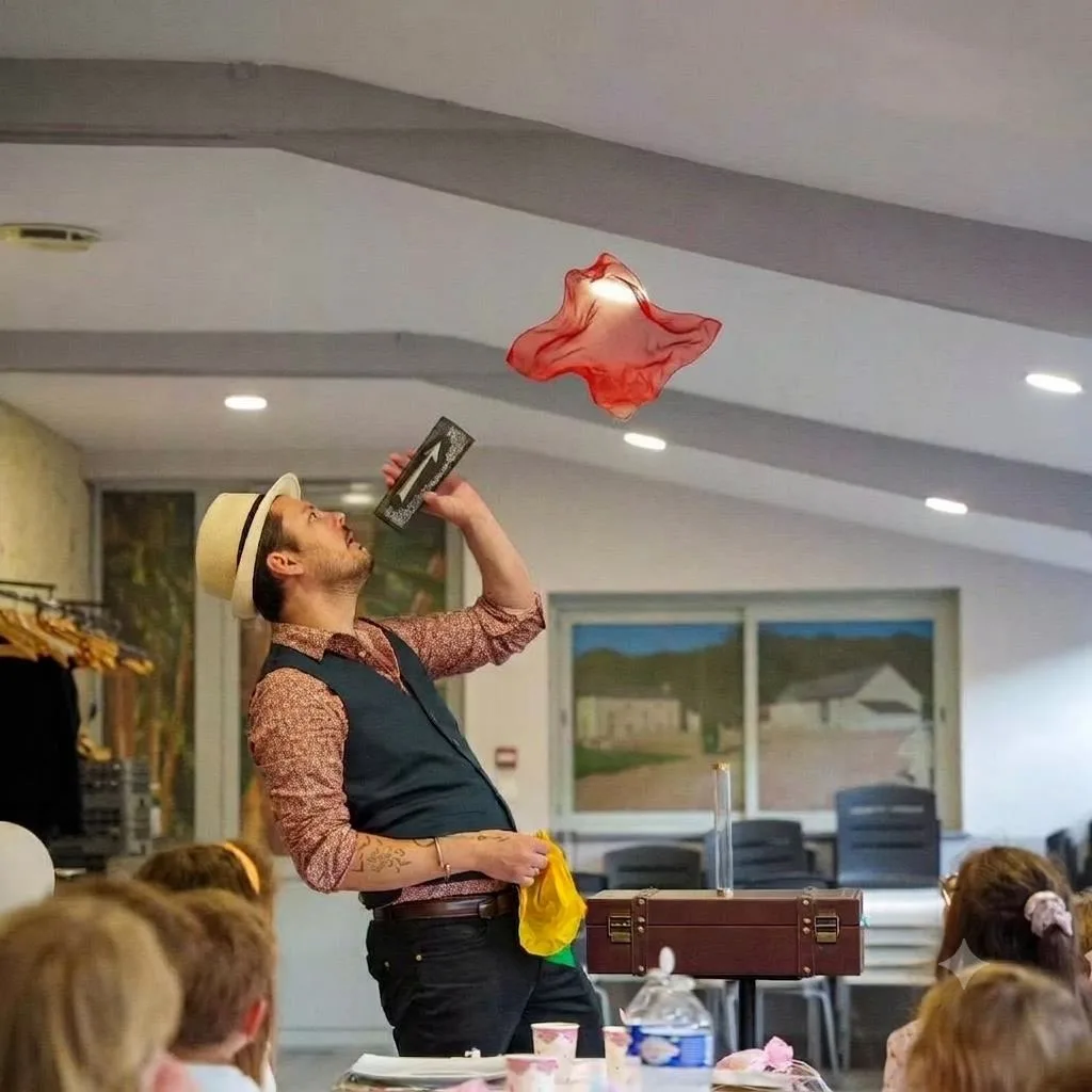 Un foulard rouge flotte en l’air au-dessus de Jérôme, devant des enfants attablés