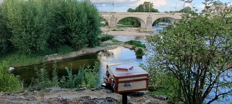 La malle de magicien posée au bord de la Loire, le pont en arrière-plan