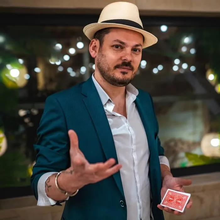 Jérôme en veste bleue, chapeau et jeu de cartes rouge à la main