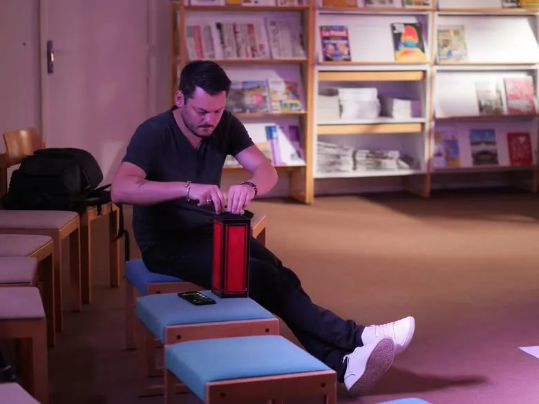 Jérôme prépare une lanterne rouge avant un spectacle, dans une médiathèque