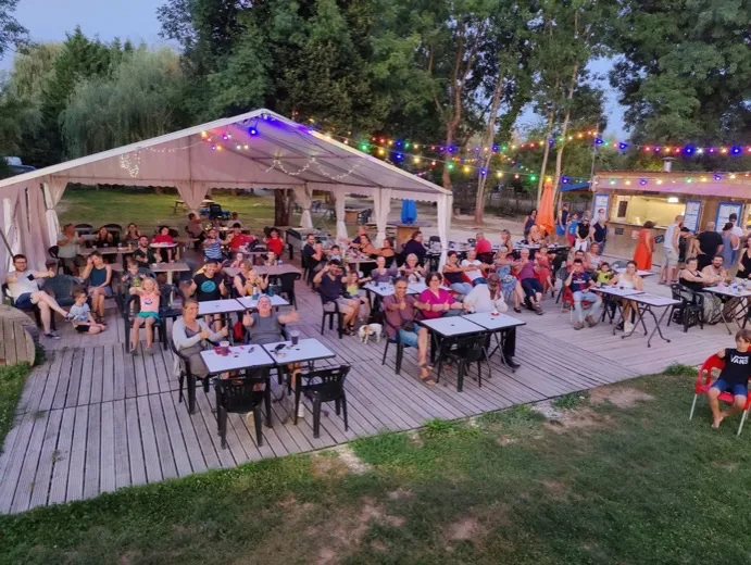 Une centaine de spectateurs attablés sous un barnum, en plein spectacle