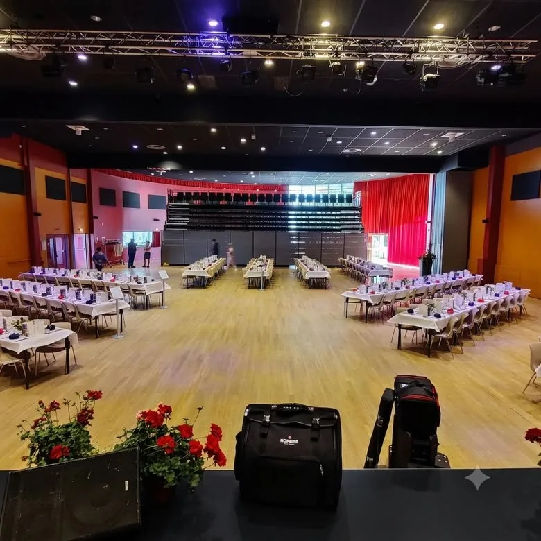 Grande salle dressée pour un banquet, la scène éclairée en rouge au fond
