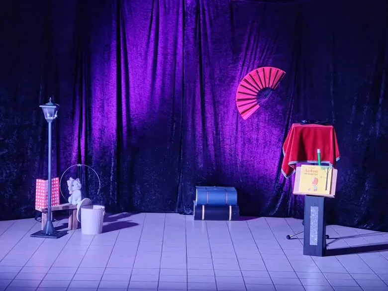Le décor de scène monté devant un rideau violet : lampadaire, éventail et guéridon nappé de rouge